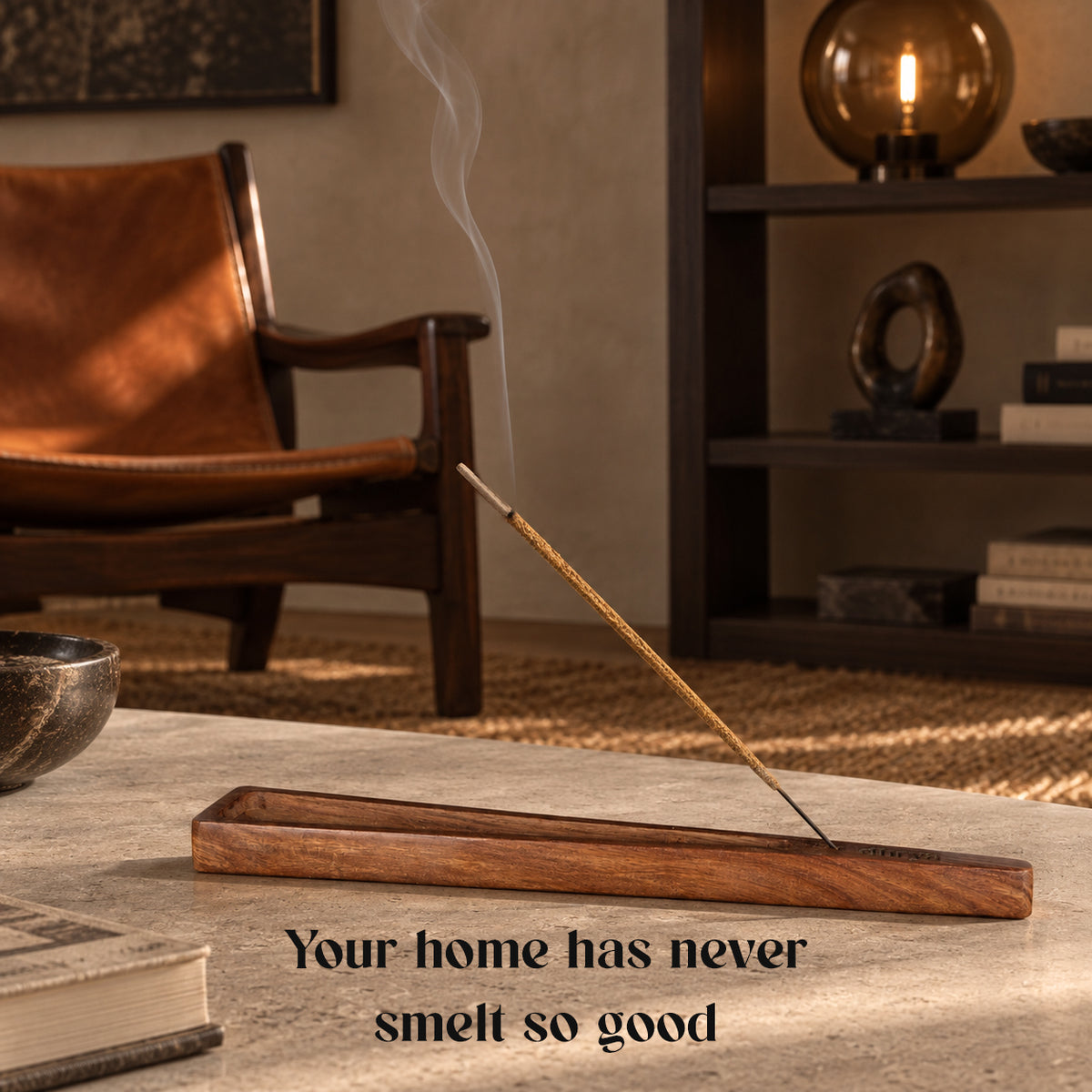 Black Oud incense stick burning in a rosewood holder in a dark living room with a leather armchair