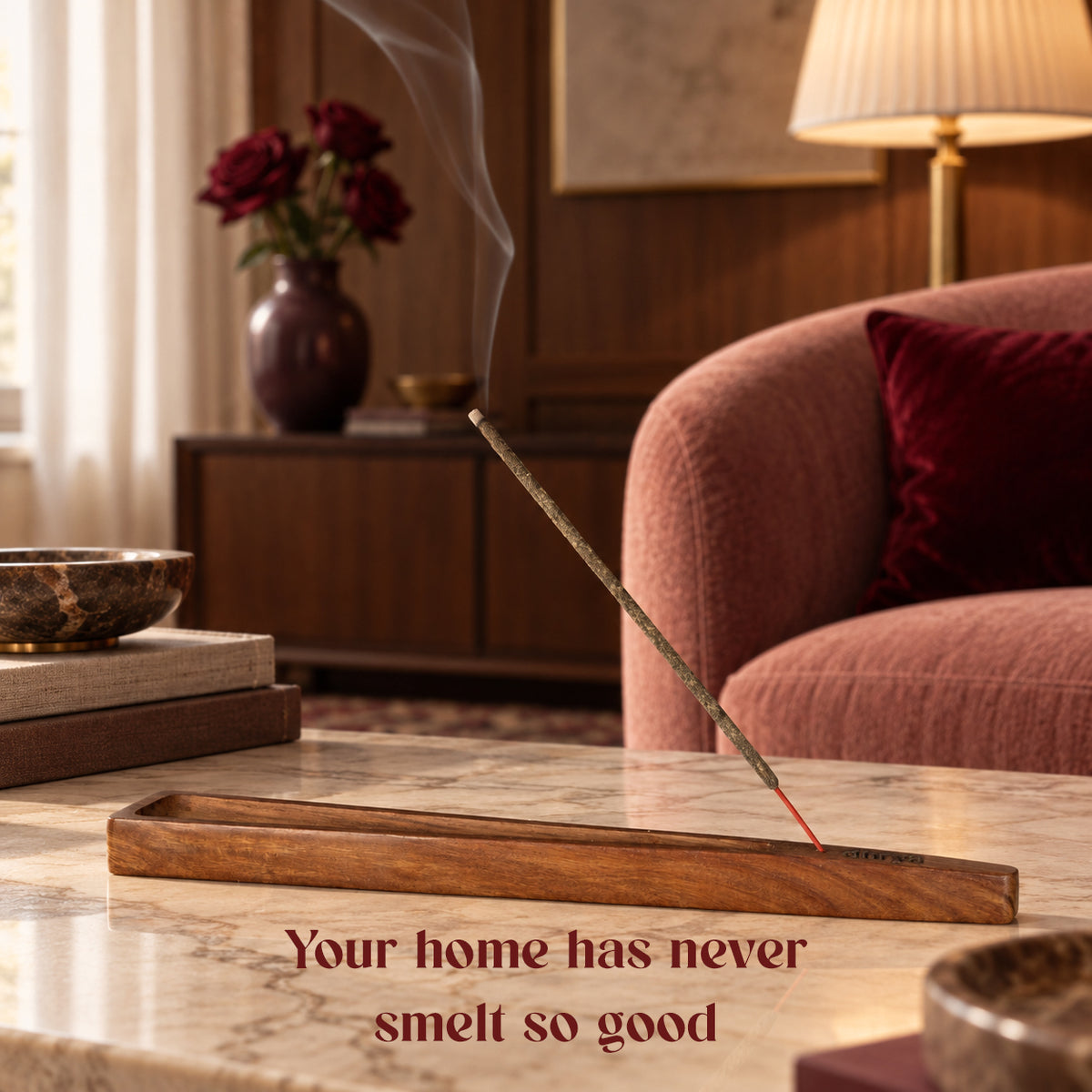 Amira Rose incense stick burning in a rosewood holder in a living room with red roses and a pink armchair